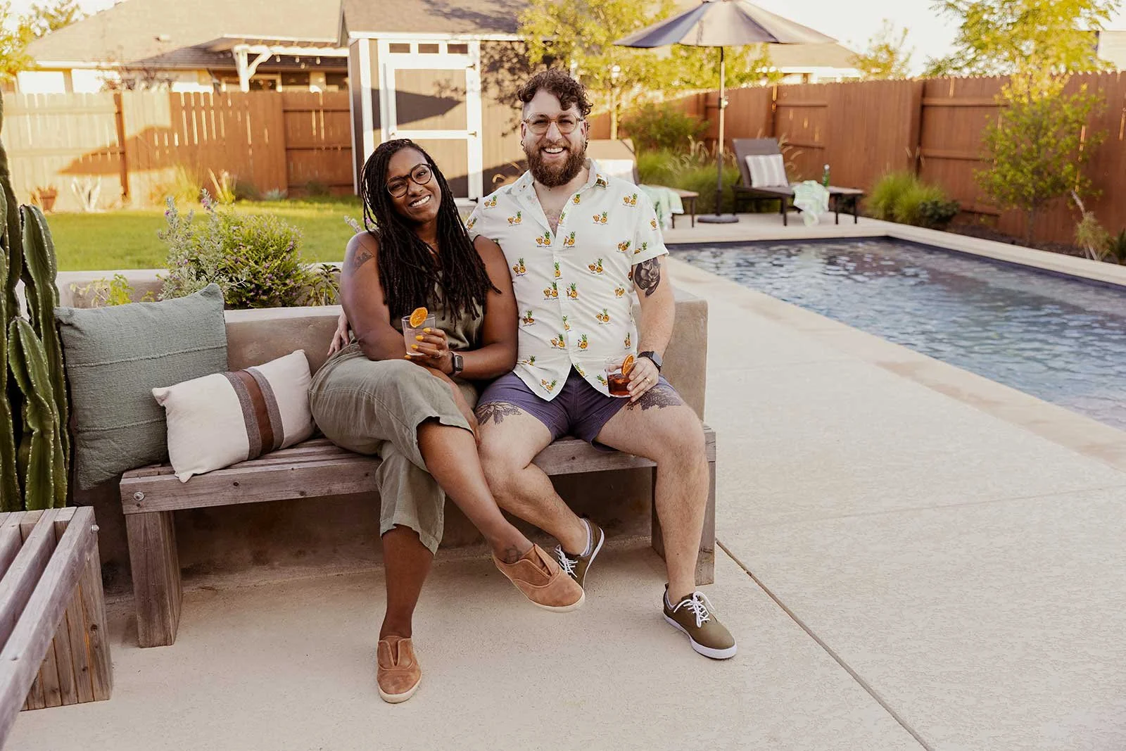 Couple with drinks enjoying their backyard with a pool