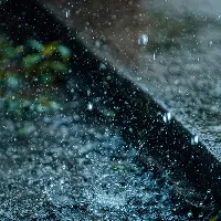 Close-up of heavy rain falling on a street gutter with splashing water