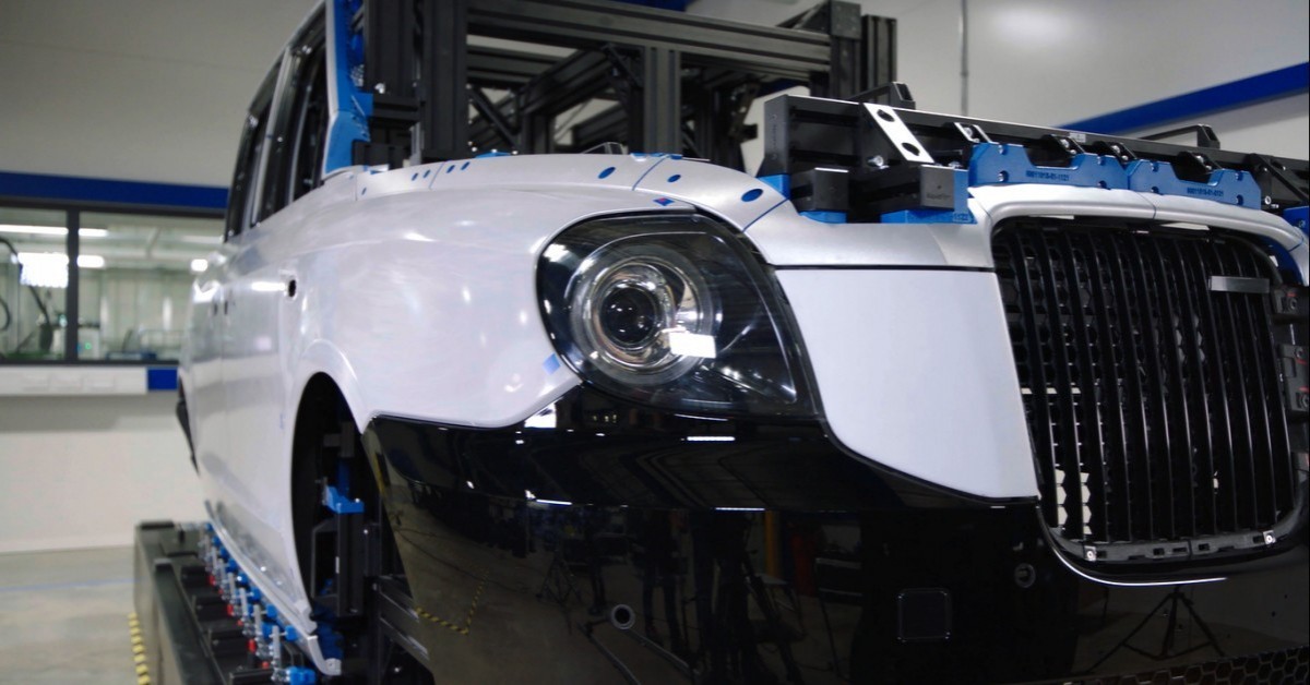 A close-up shot of a headlight and front bumper attached to the cube of a traditional London taxi.