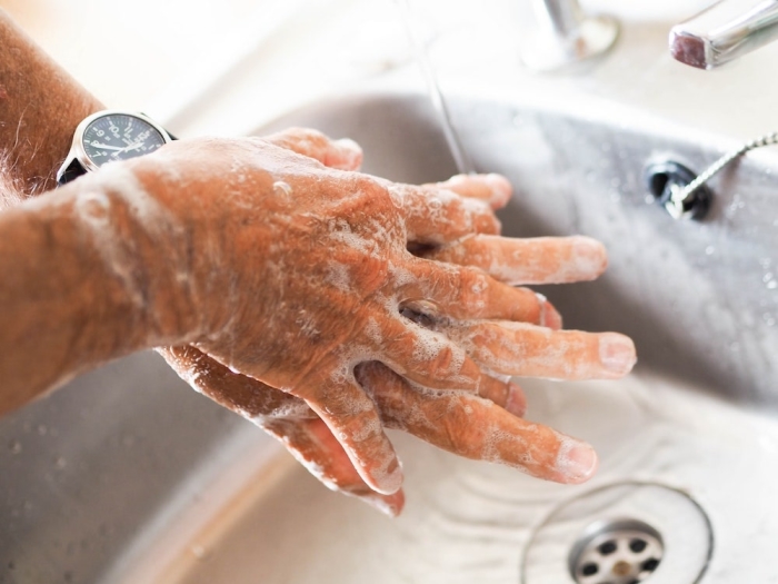 man washing hands with soapy water.