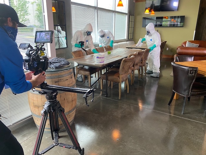 camera man recording janitors in full ppe cleaning office table.