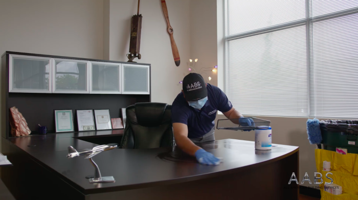 man cleaning office desk with wipe.
