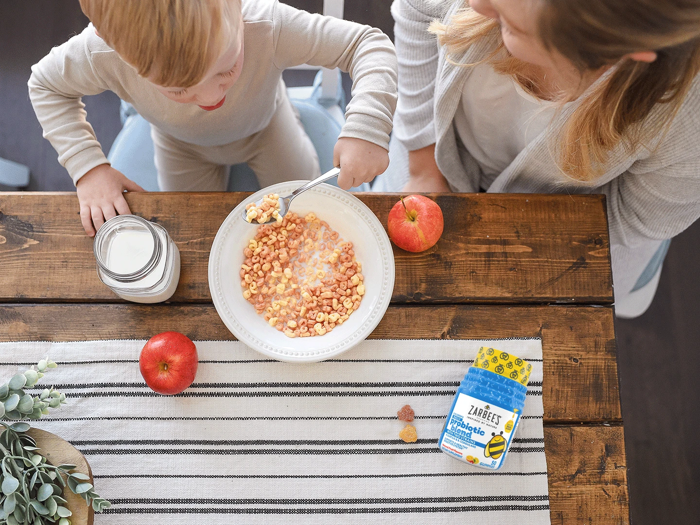 Mother and child at table with bowl of cereal and Zarbee's Daily Probiotic Blend bottle