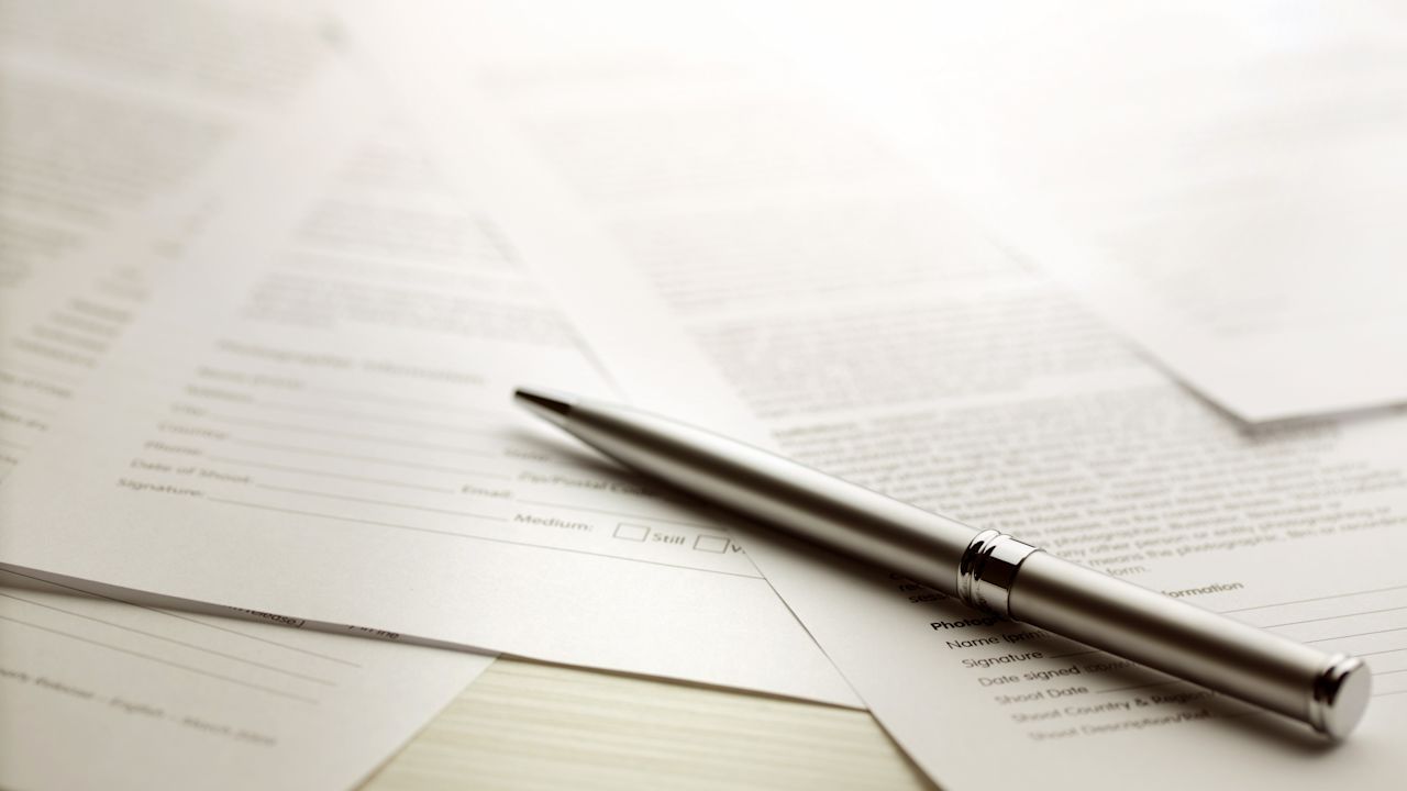Ein silberner Stift liegt auf Vertragsdokumenten