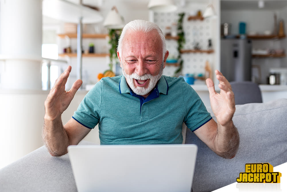 Mann sitzt vorm Laptop und freut sich.