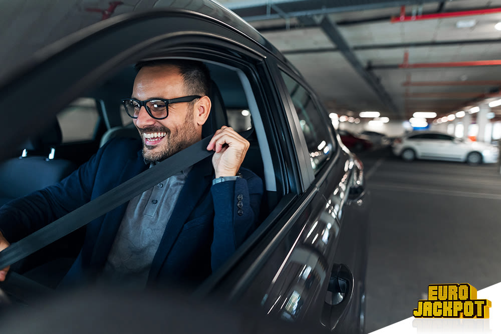 Ein Mann sitzt im Auto und schnallt sich an.