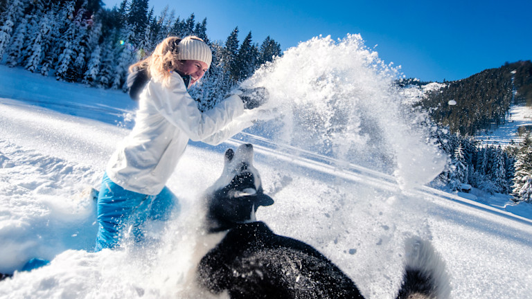 Frau spaziert durch den Wald im Schnee