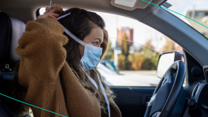 Woman putting on mask in car.