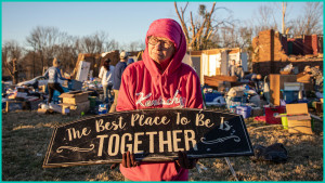 Kitty Williams Holds up a sign that survived the storm as her friends and family help gather her belongings of what is left of his house after extreme weather hit the area,