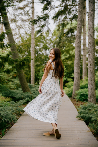 Young woman smiling while walking on a wooden boardwalk in a forest