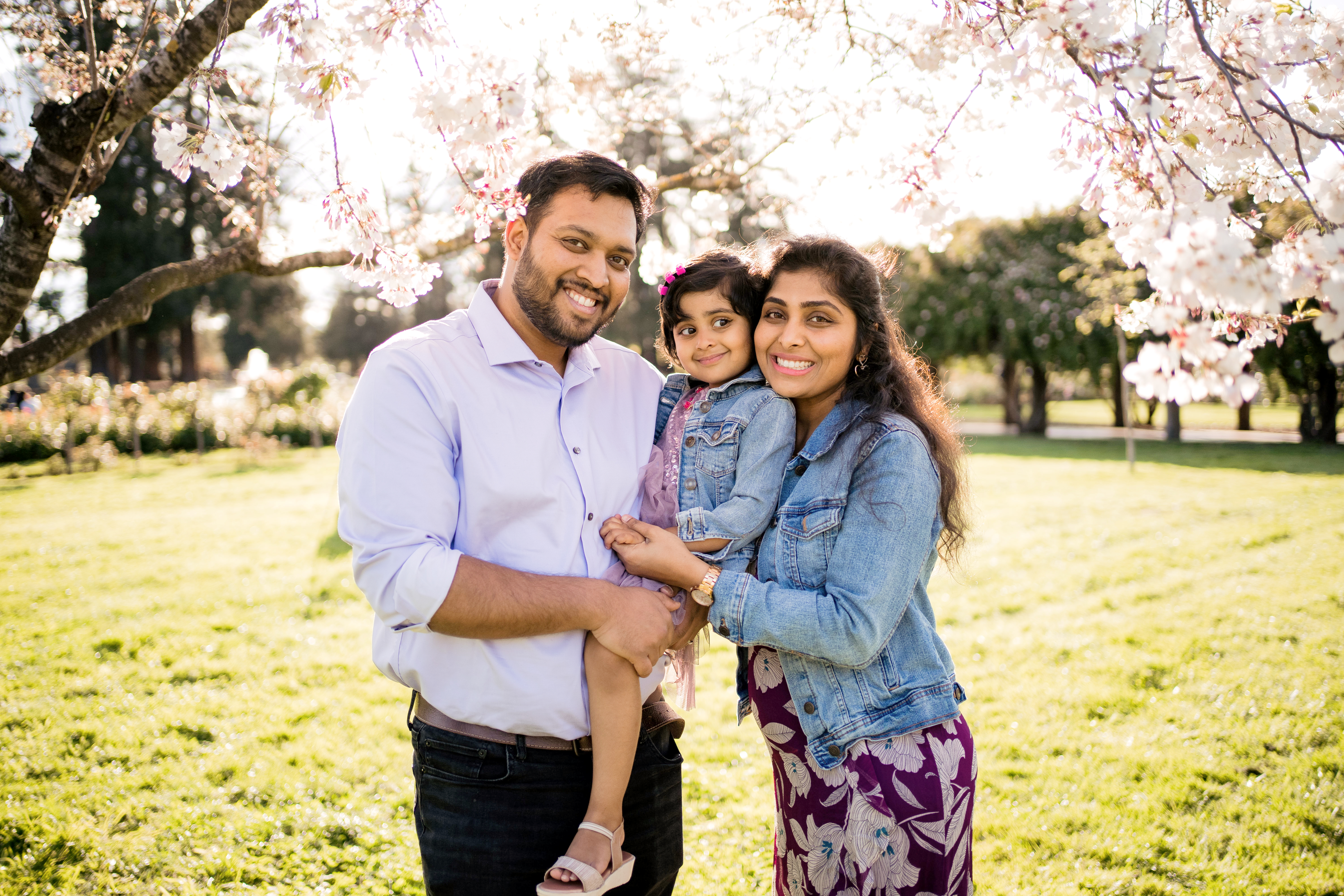Happy family smiling under cherry blossom trees during a free Shoott professional photography session