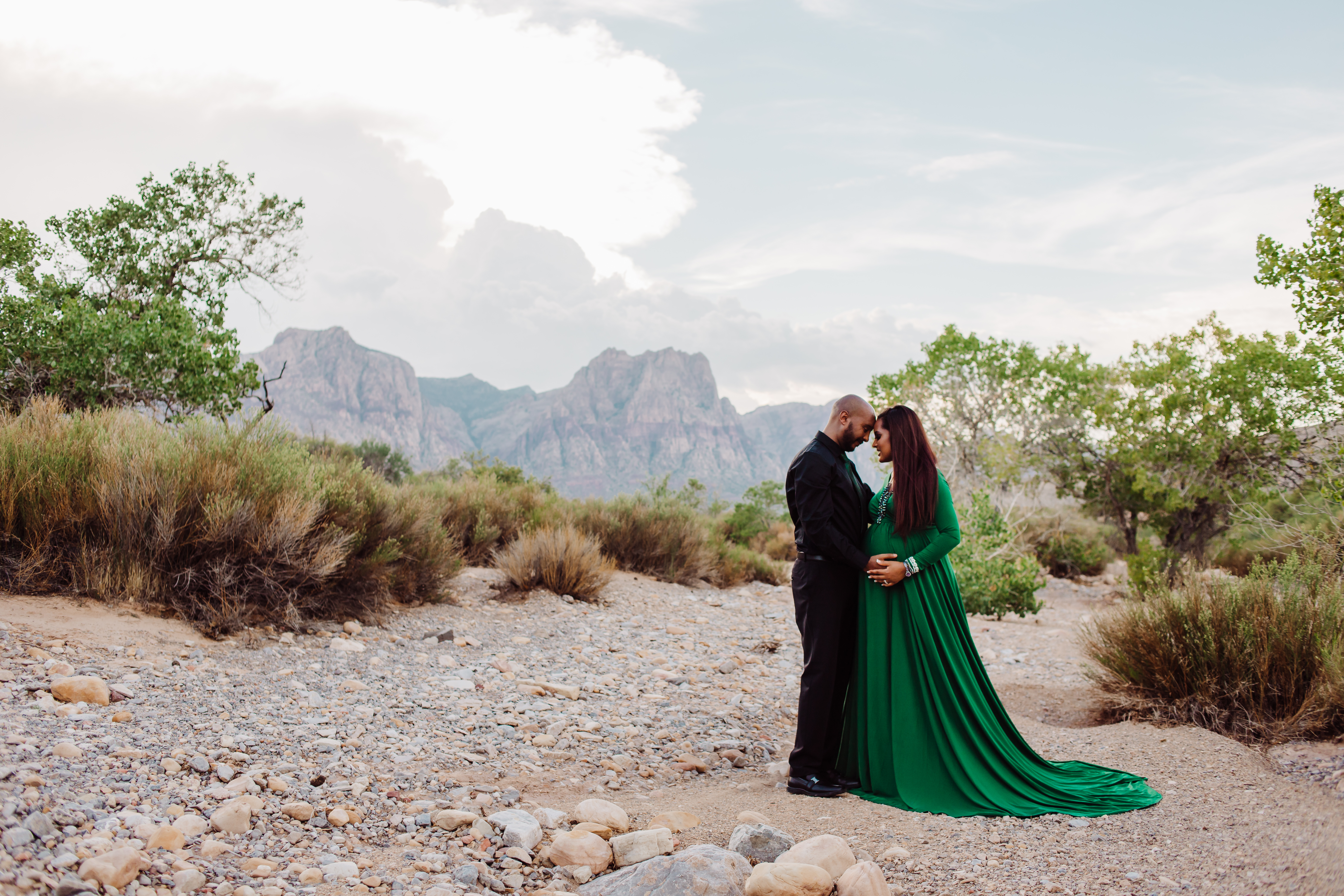 Couple posing in desert landscape with mountain backdrop during a professional Shoott photo shoot.