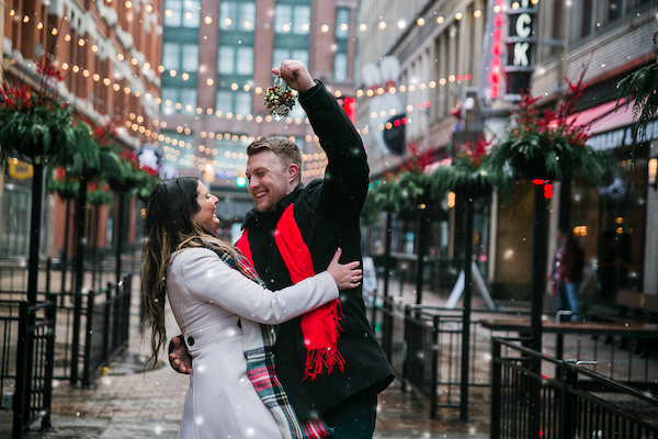 Couple dancing and laughing under mistletoe on a decorated city street
