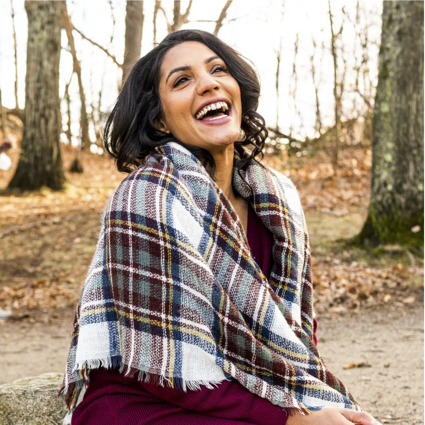 Woman laughing wrapped in a plaid blanket scarf outdoors in a park during free professional dating profile photo session with Shoott in Houston