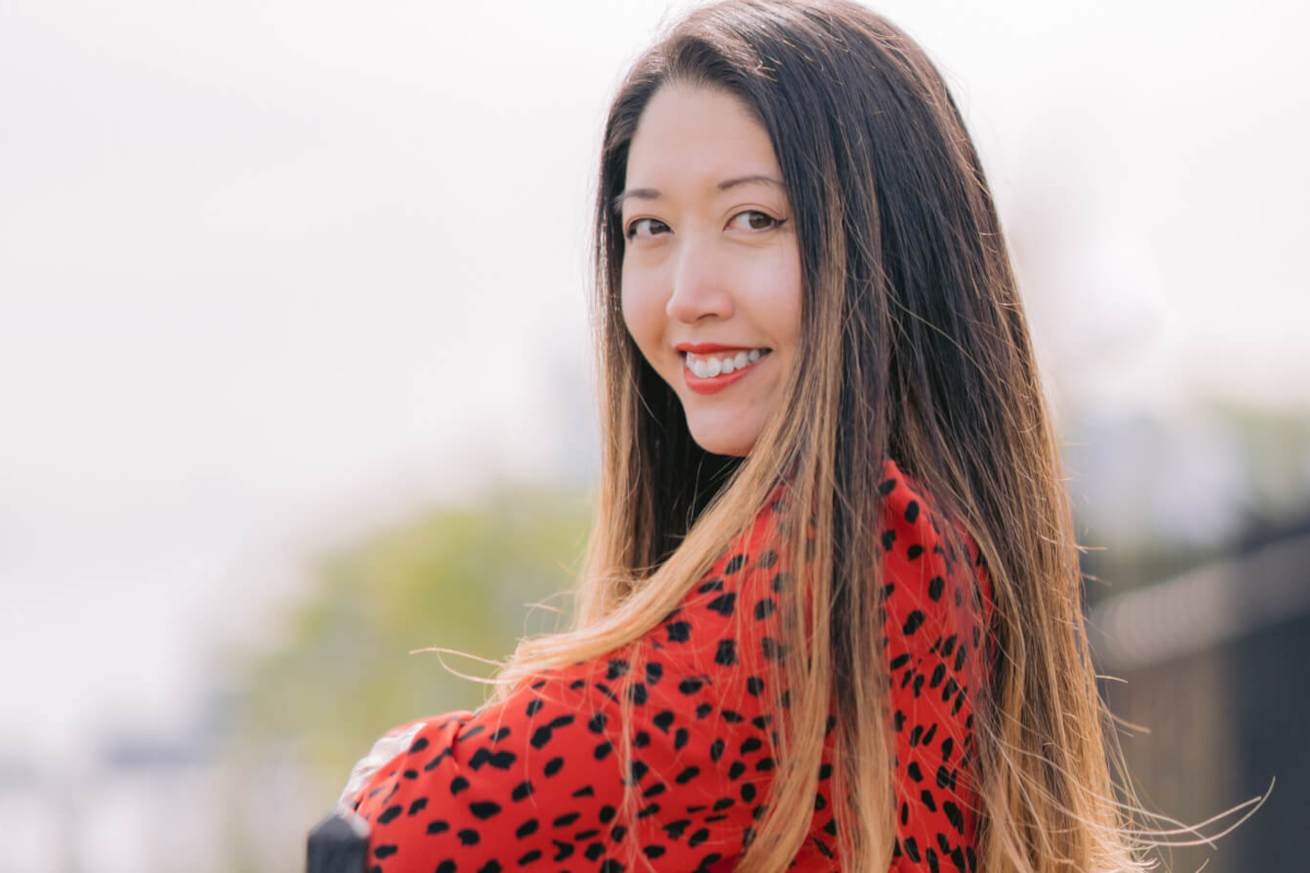 https:A smiling woman in a red polka dot blouse looking over her shoulder