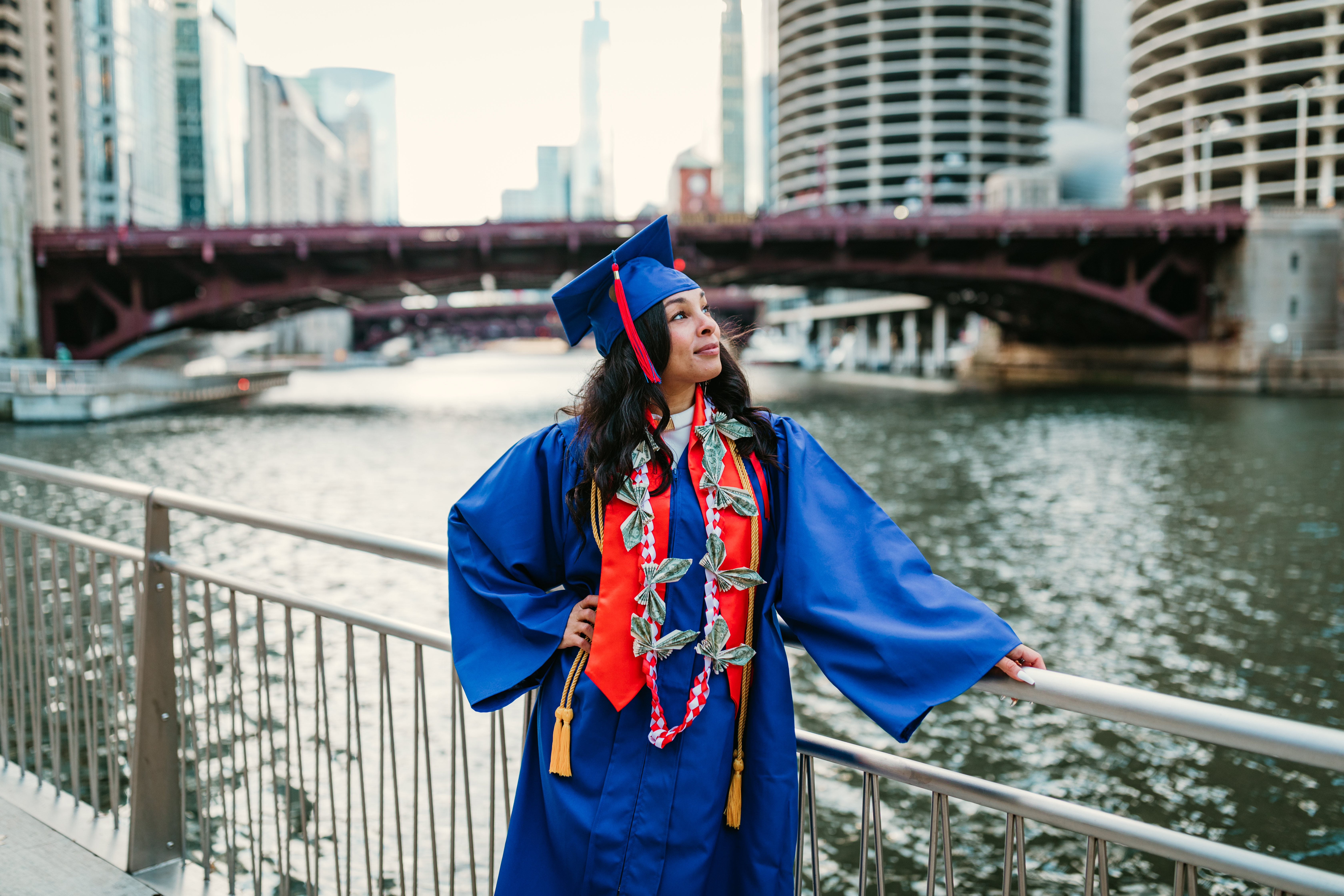  Graduate in blue cap and gown celebrating by the Chicago Riverwalk during a free professional graduation photo session with Shoott