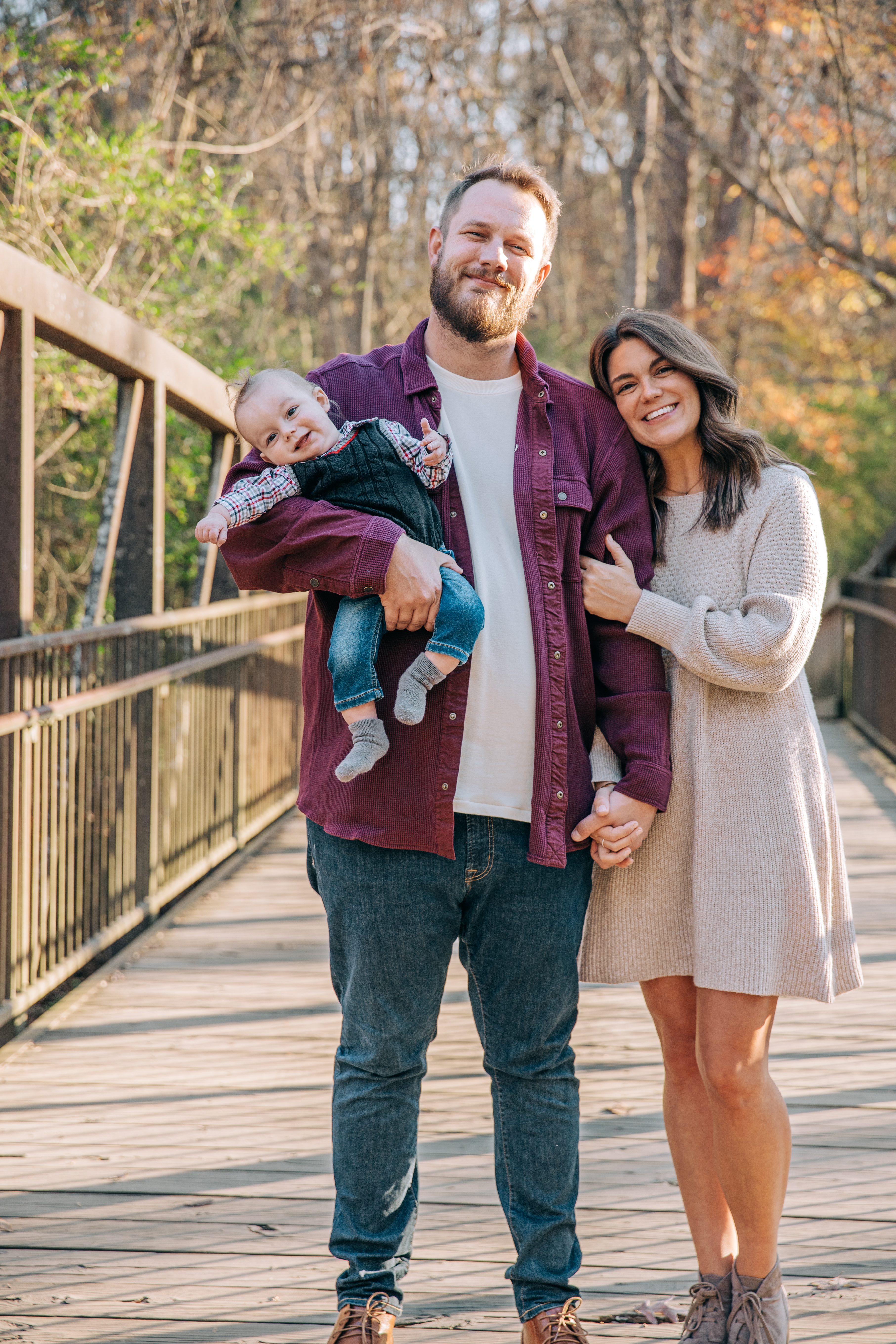 Family with a baby during a photoshoot on the wooden footbridge at East Cobb Park, captured by a Shoott photographer.