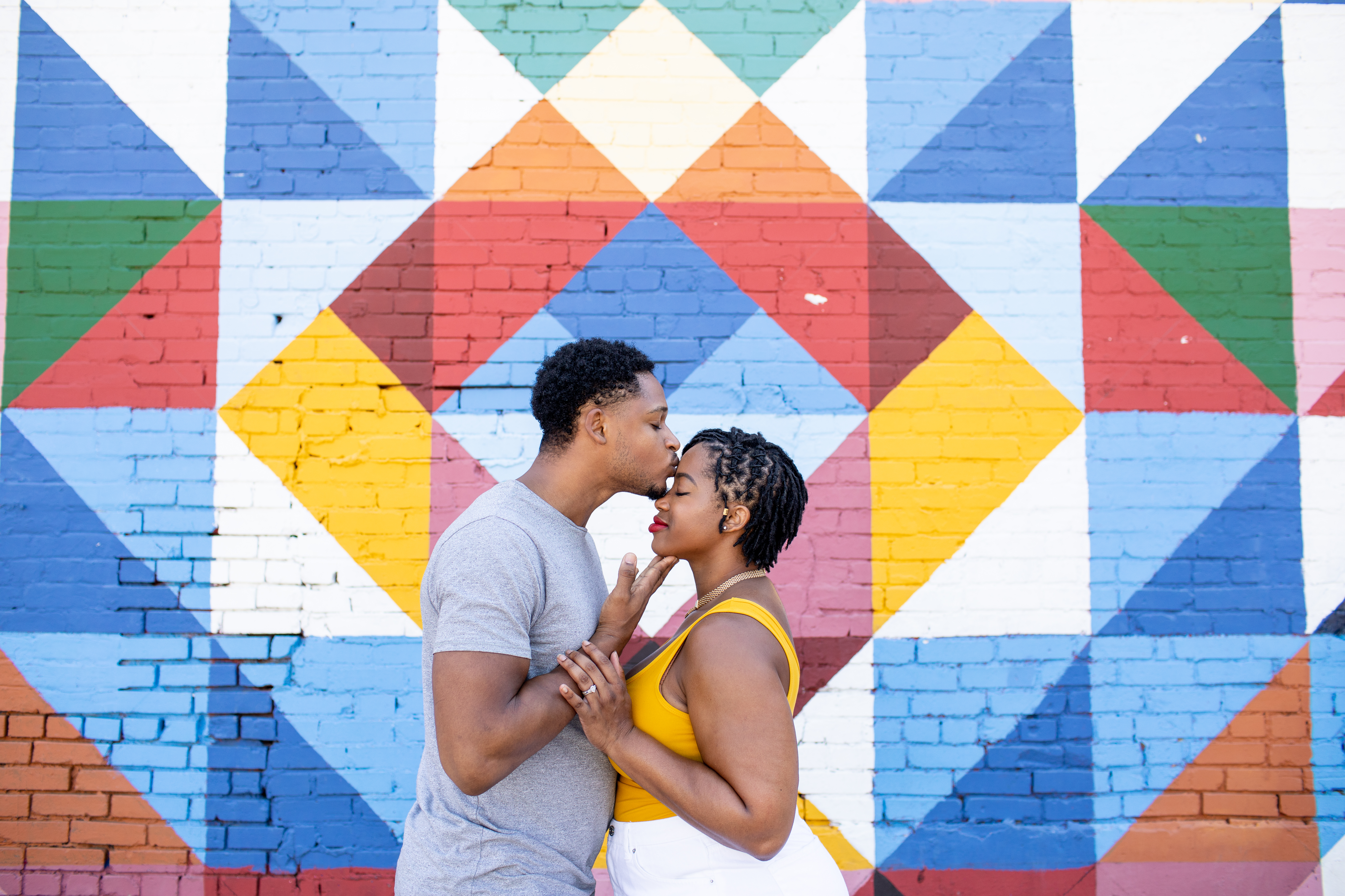 Couple about to kiss in front of a vibrant geometric mural during a professional Shoott photo shoot.