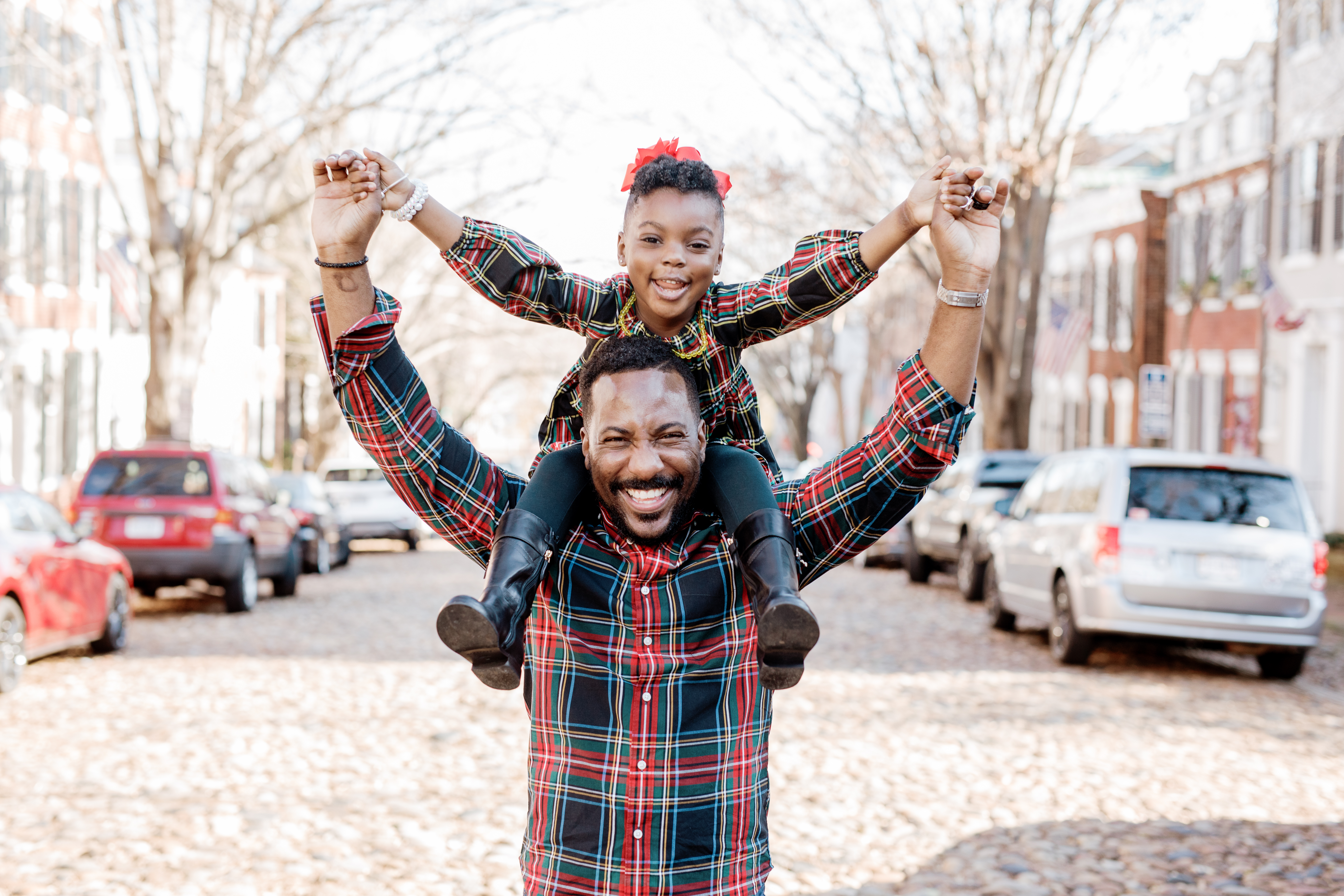 Dad carrying daughter on his shoulders as she spreads her arms during a free Shoott lifestyle photography session