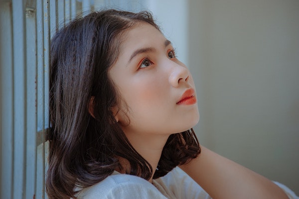 Young woman looking upwards with a contemplative expression.