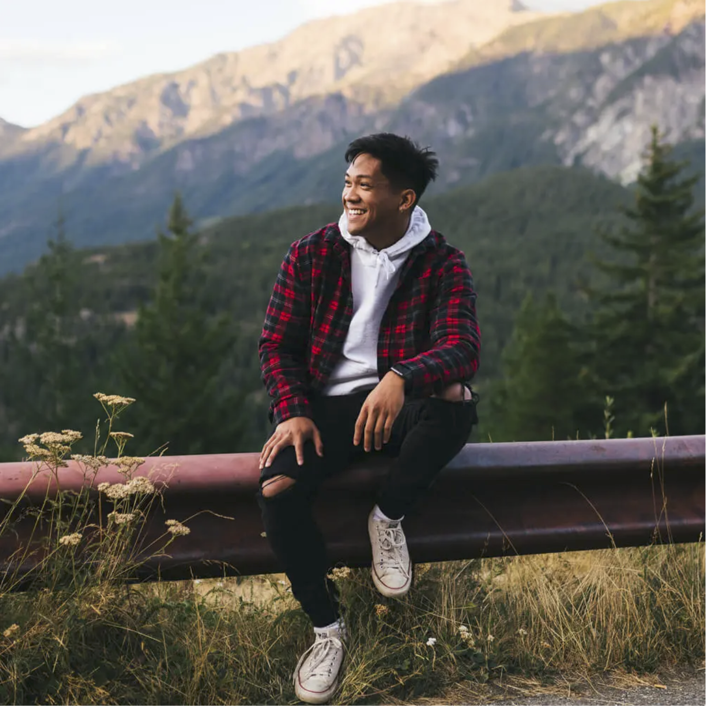 Man in plaid jacket smiling on a mountain road during free professional dating profile photo session with Shoott in Houston 