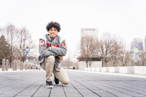 Teenager squatted down on an empty city street smiling at the camera