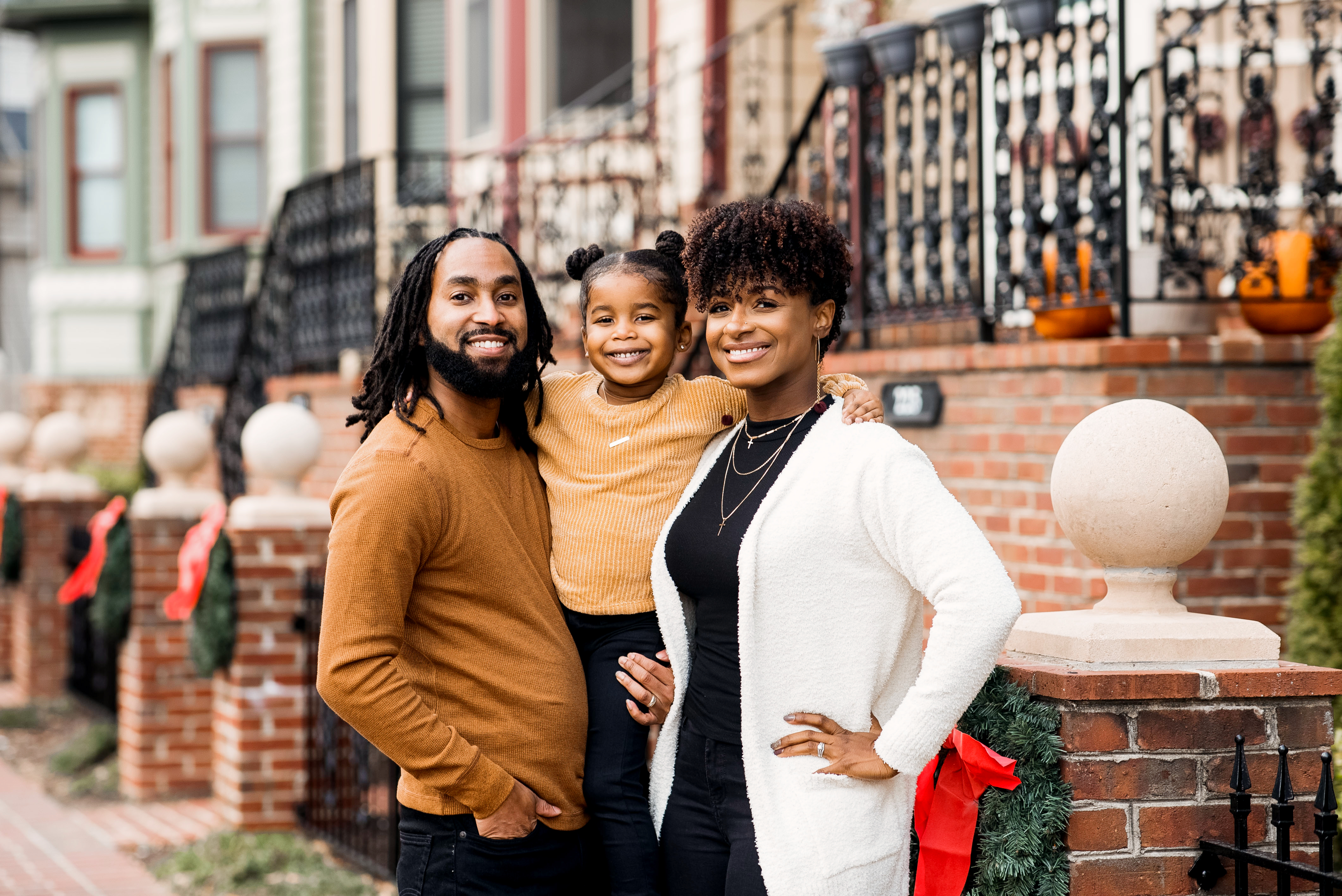 Family wearing coordinated tan, cream, and burgundy outfits for outdoor holiday photos