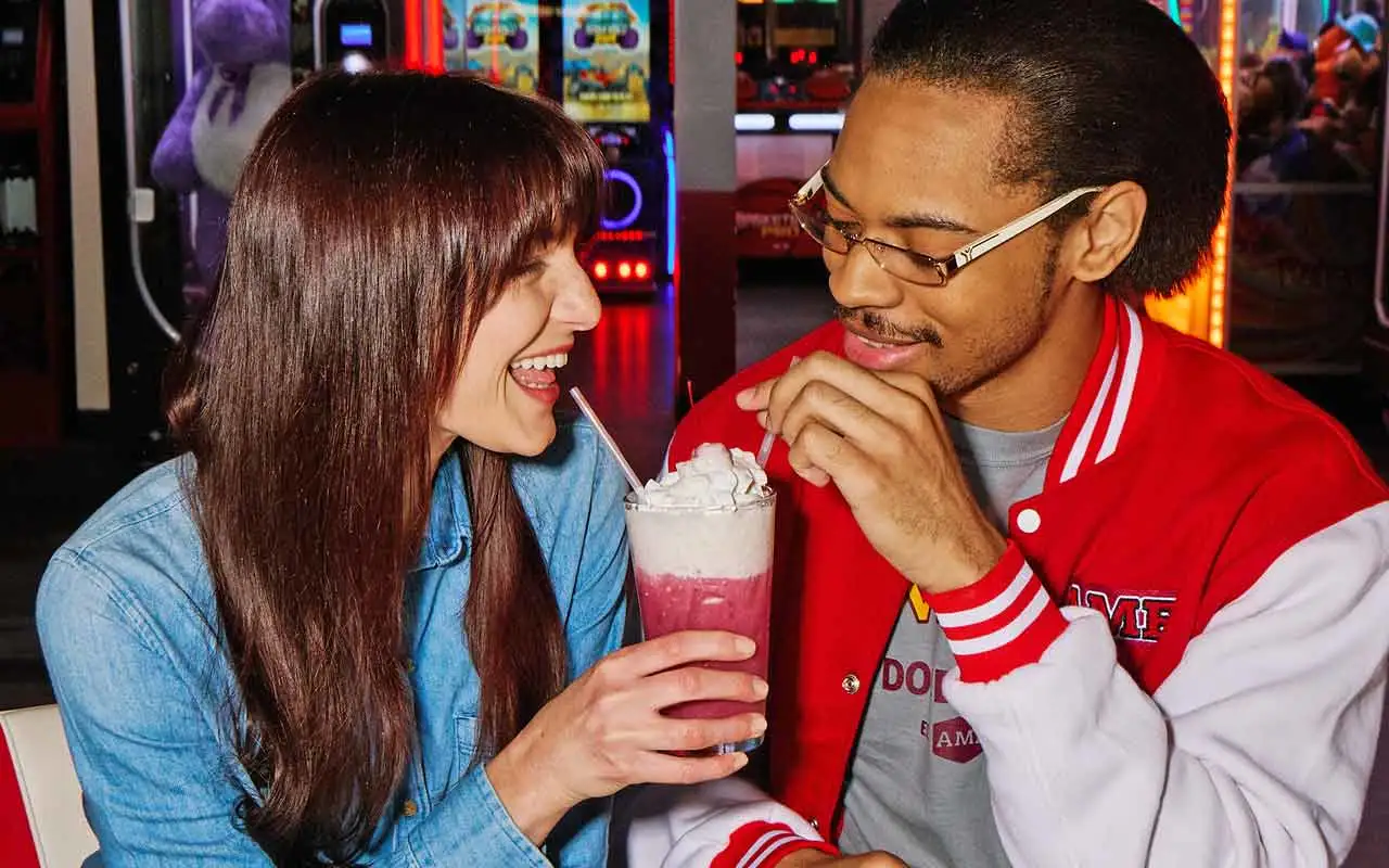 A couple enjoying a milkshake together at an AMF bowling center.