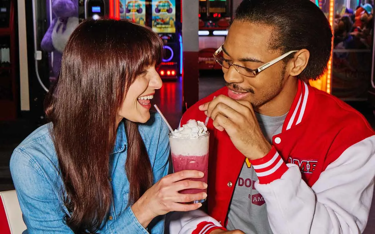 A couple enjoying a milkshake together at an AMF bowling center.