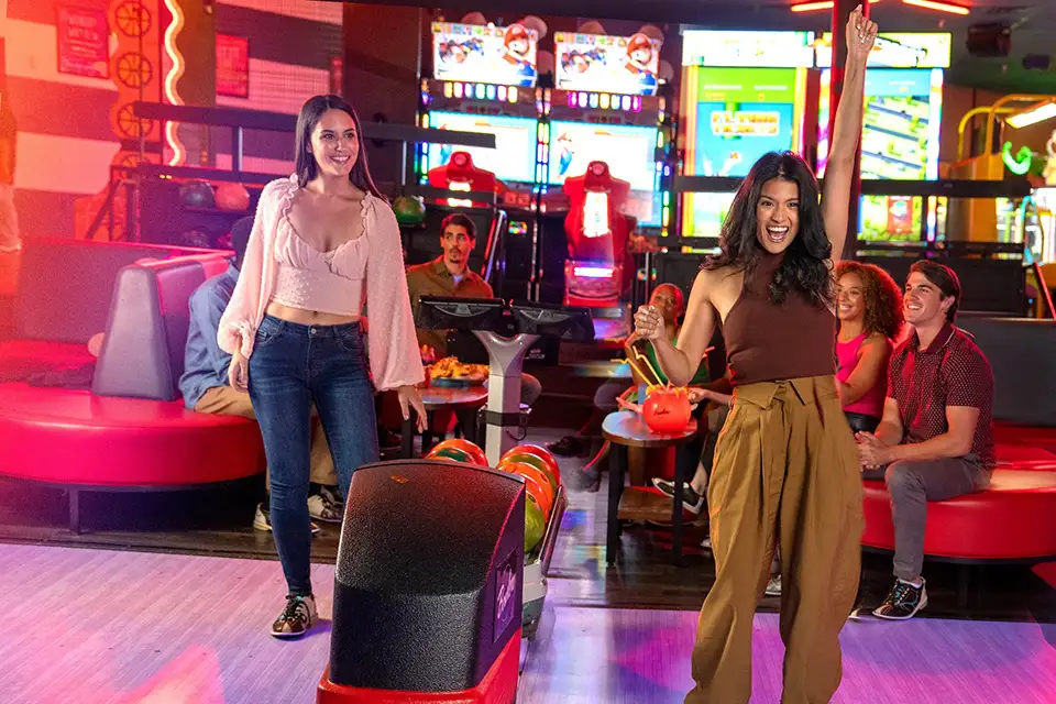 Two girls laughing and having fun while bowling.