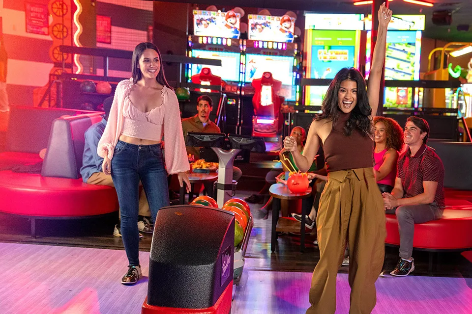 Two girls laughing and having fun while bowling.