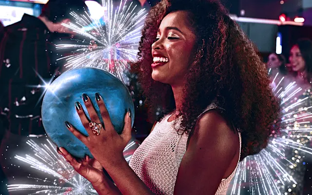 Smiling girl dressed in silver holding a bowling ball