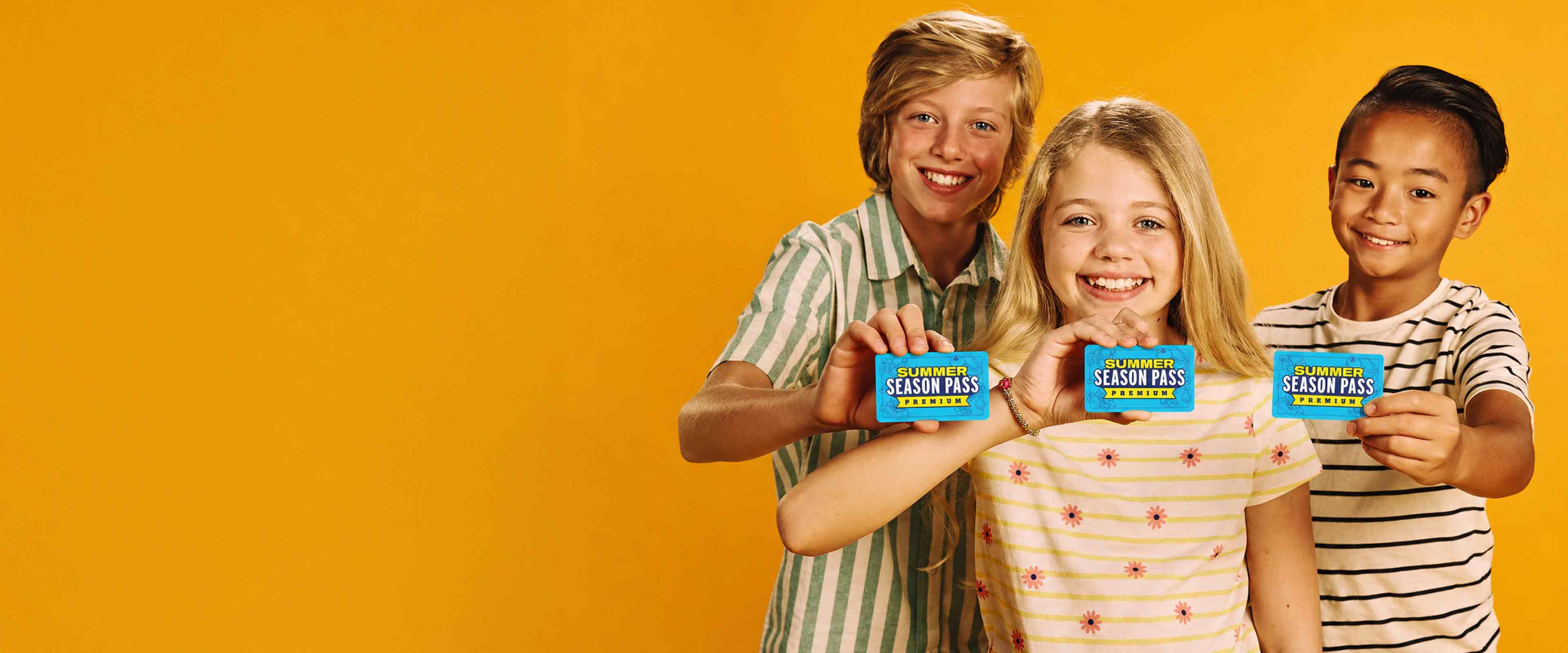 Girl holding a Summer Season Pass card in front of colorful bowling balls at a bowling center.