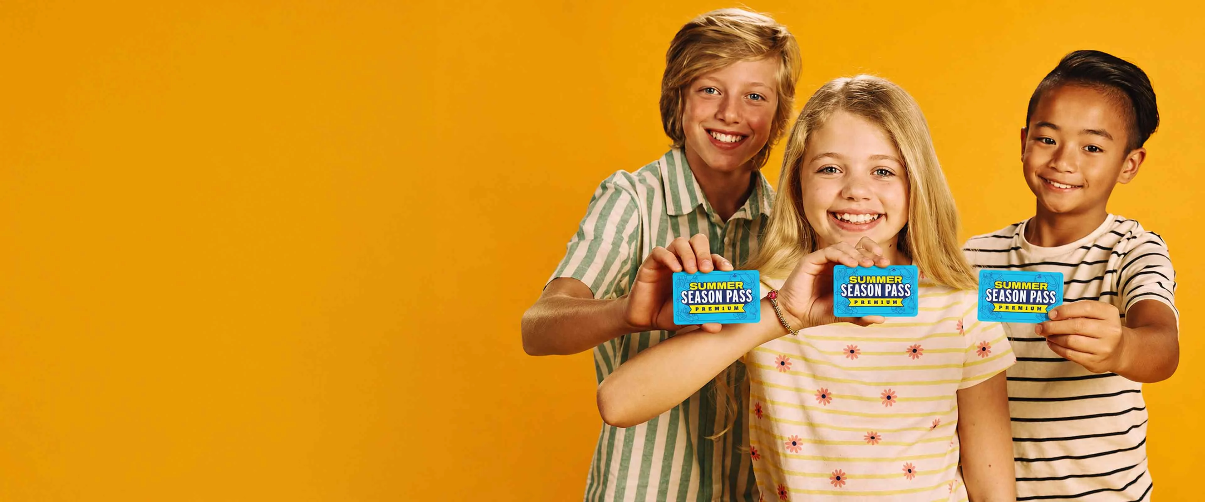 Girl holding a Summer Season Pass card in front of colorful bowling balls at a bowling center.