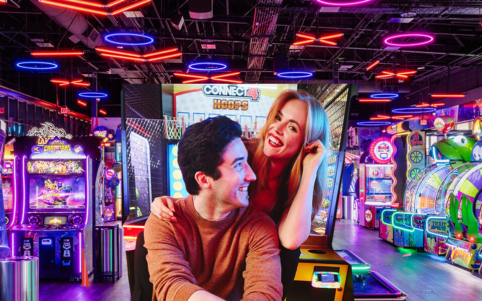 Two people smiling at each other with an arcade in the background