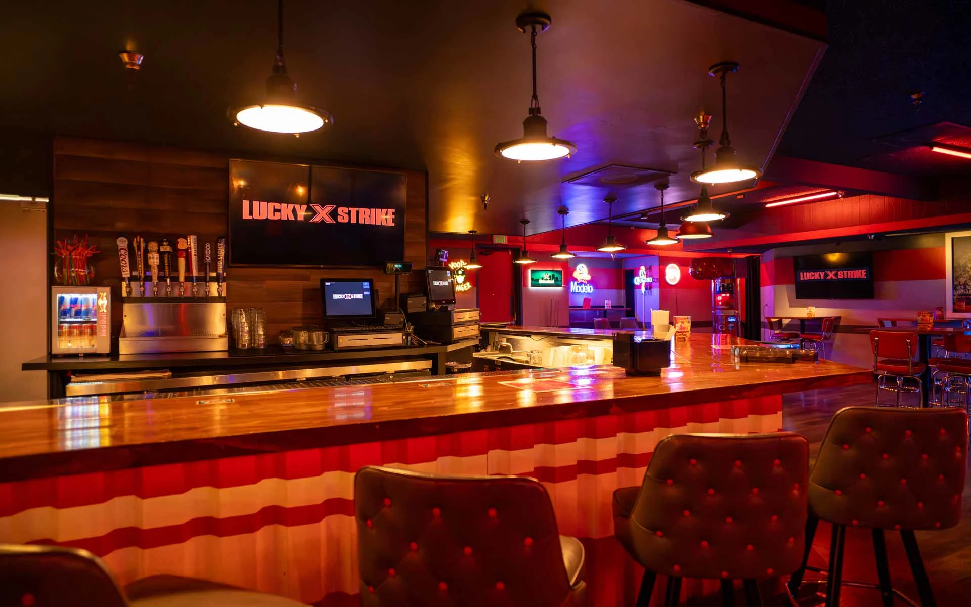 Stylish bar at Lucky Strike with wood countertops, pendant lighting, beer taps, and a relaxed lounge atmosphere with neon accents.