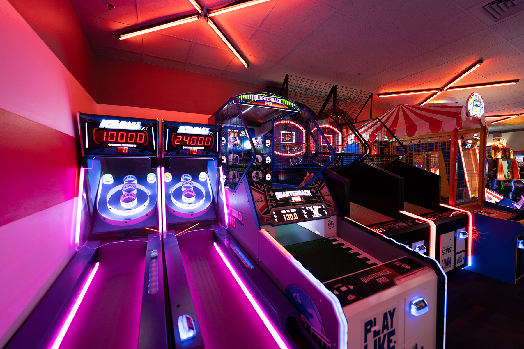 Neon-lit skee ball game with arcade games in the background.