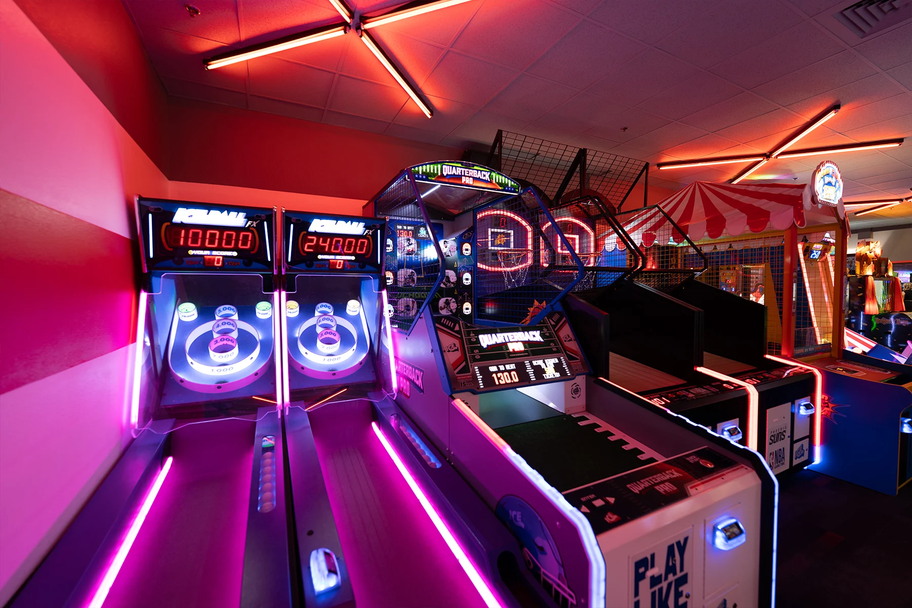 Neon-lit skee ball game with arcade games in the background.