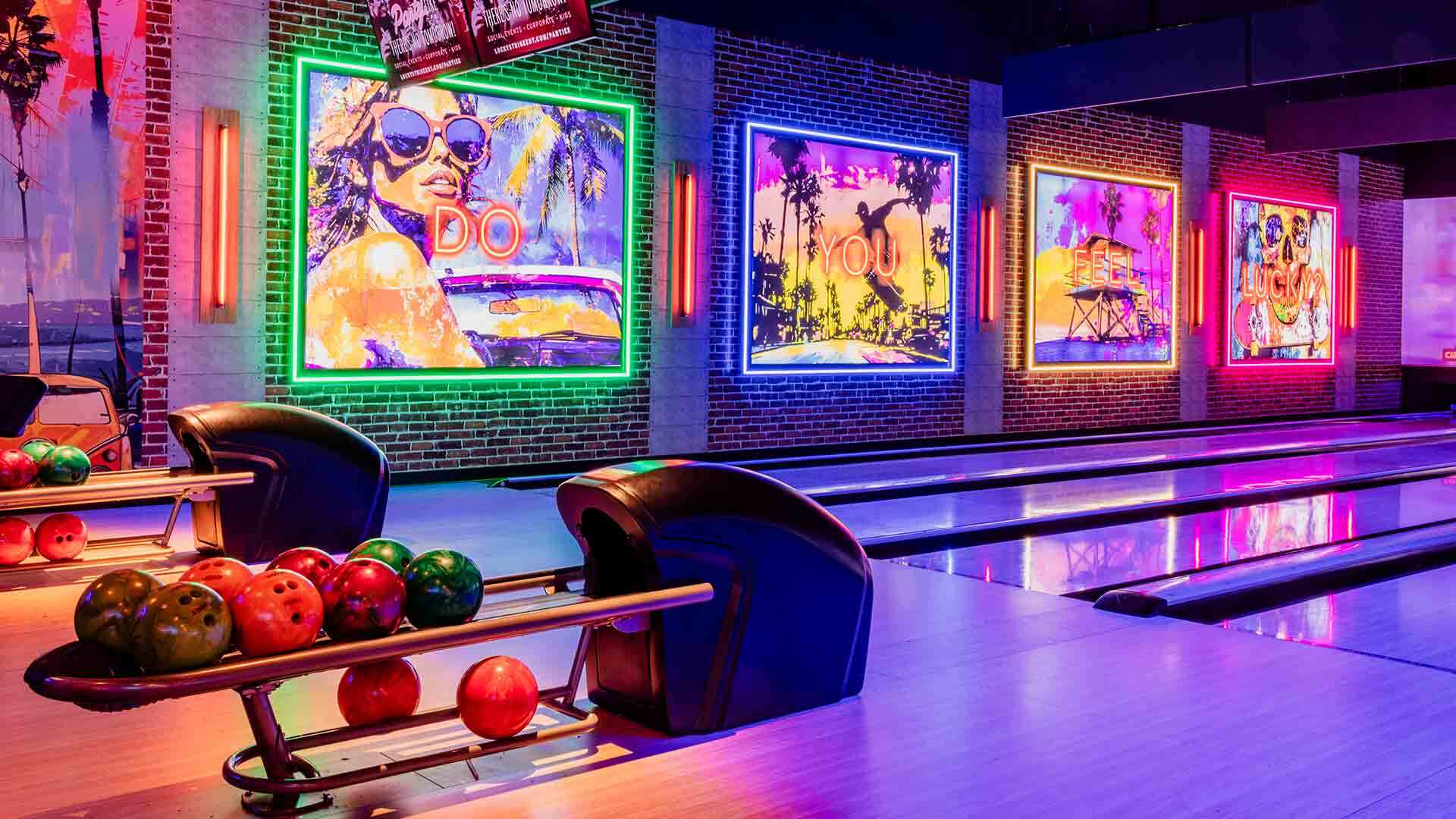 Beautiful bowling lanes with backlights and large neon light murals in the background.