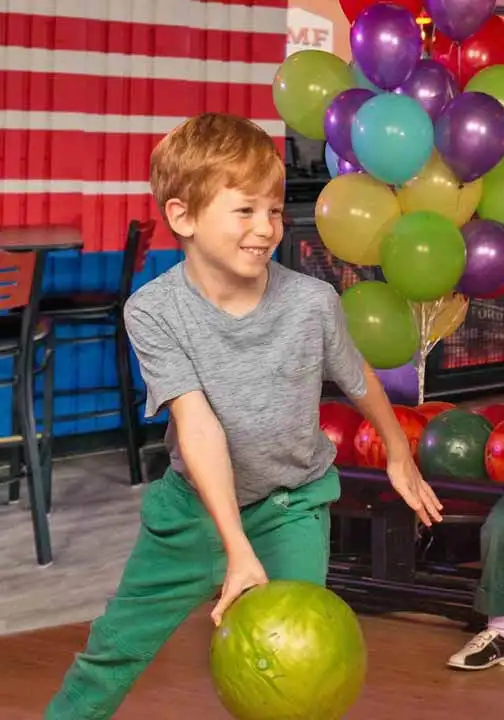 A boy bowling at his birthday party at an AMF center.