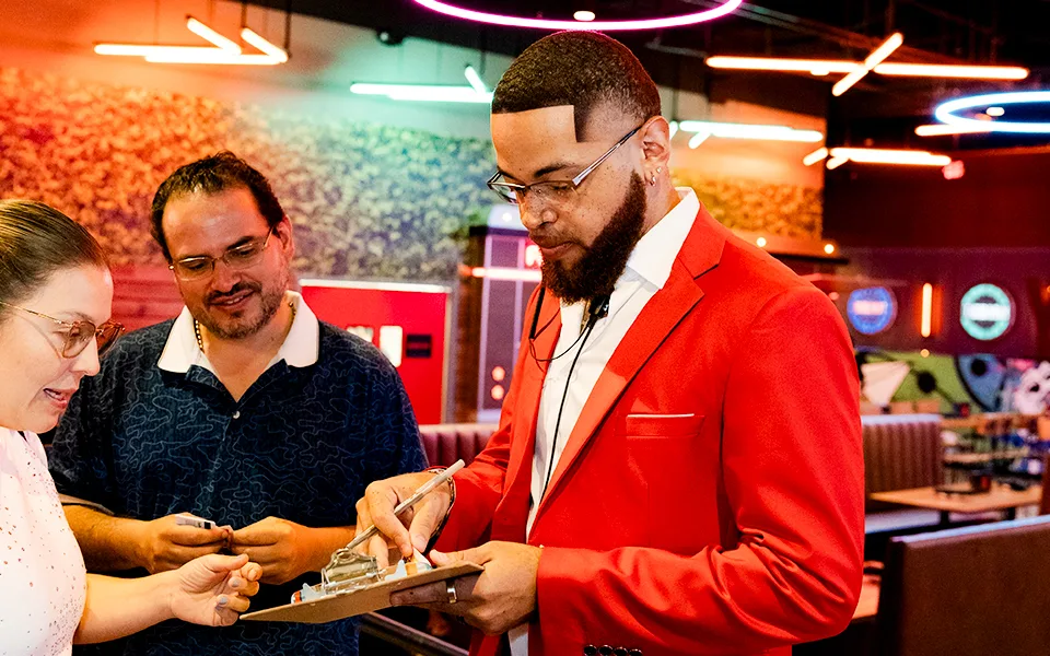 Man in red a dress coat reviewing a clipboard with guests.