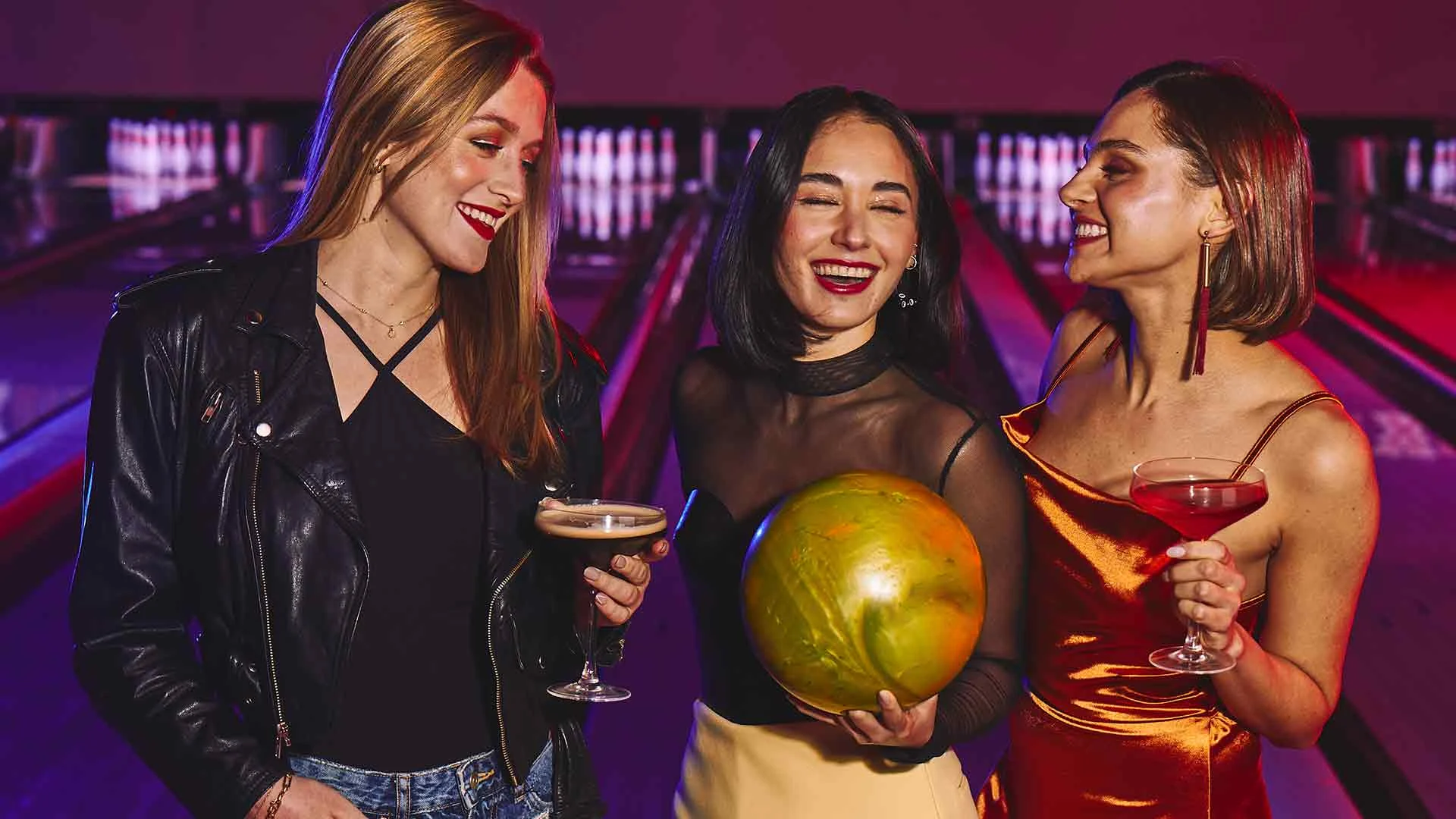 Friends bowling and enjoying cocktails at Lucky Strike.