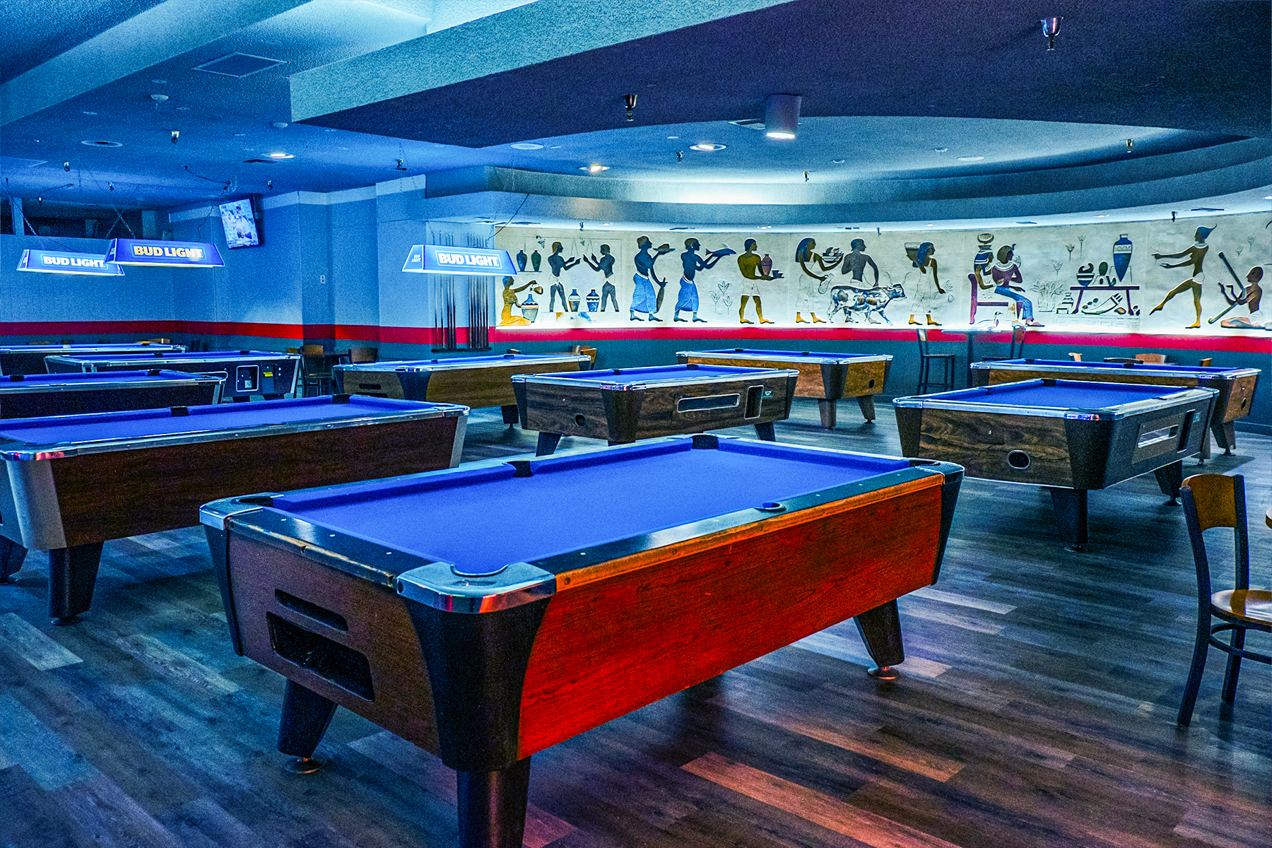 Blue billiards table in a large room with classic wood floors