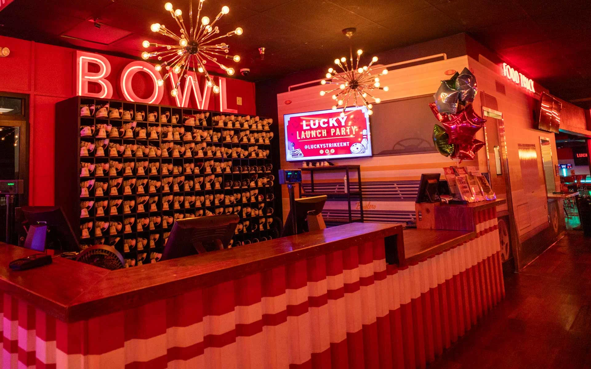 Lucky Strike front desk with bowling shoe wall, check-in counter, and modern signage under warm ambient lighting.