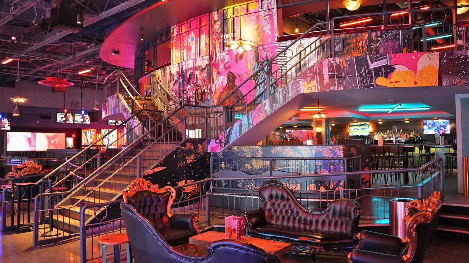 Upscale lounge seating and large staircase leading to a second level with a colorful mural.