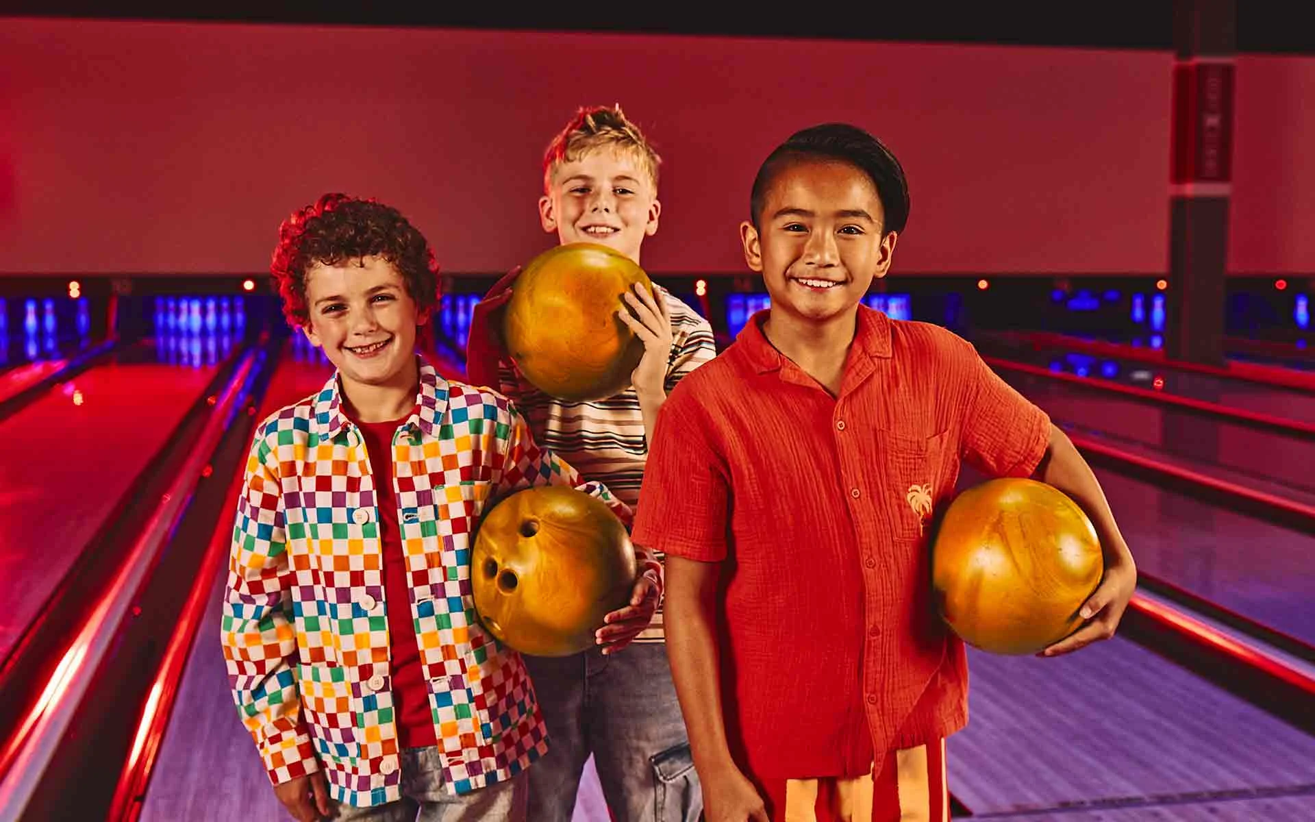 Kids bowling together with bright balls on the lanes.
