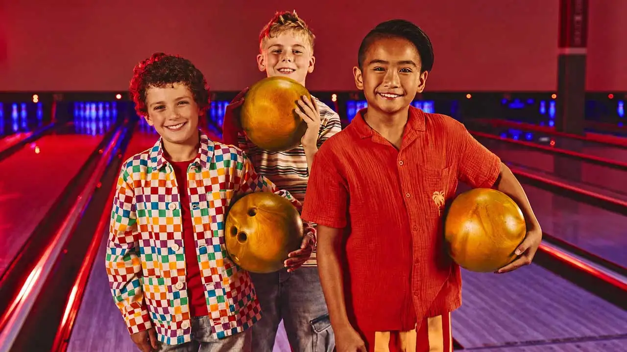 Kids bowling together with bright balls on the lanes.