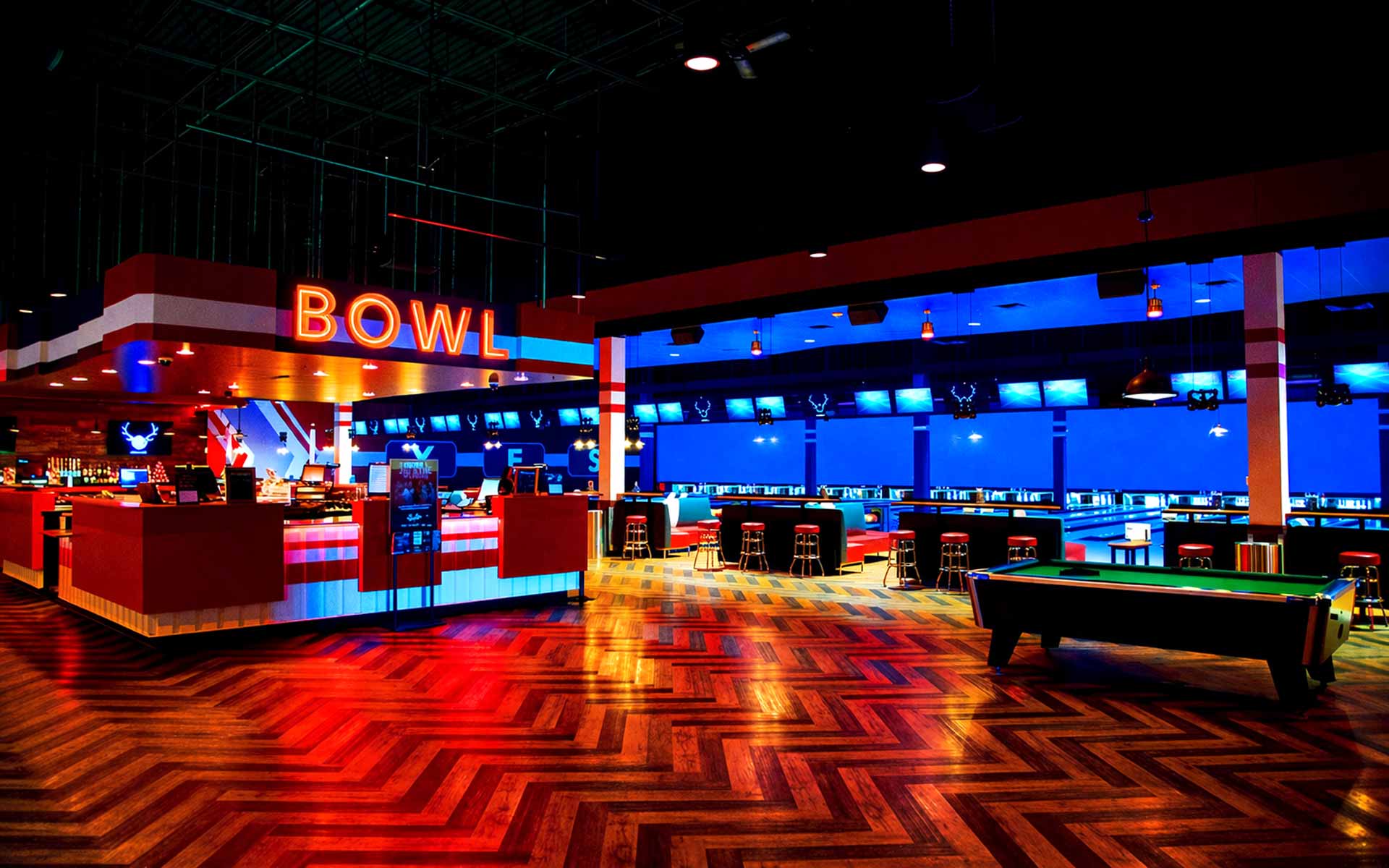 Upscale bowling center featuring lanes, bar seating, and a pool table with colorful lighting in a lively Lucky Strike entertainment venue.