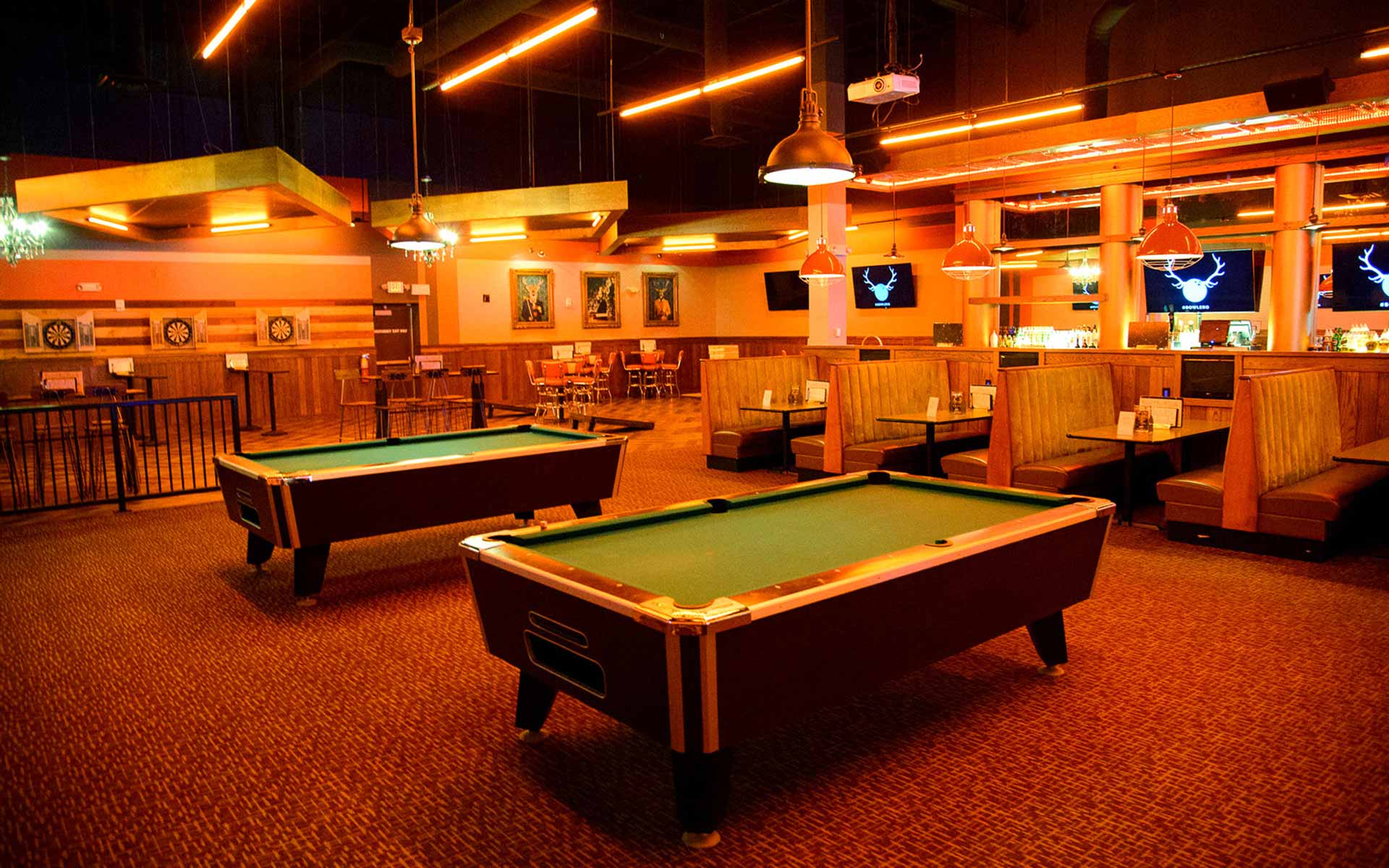 Stylish lounge area with pool tables, booth seating, and warm lighting in a modern Lucky Strike bowling and entertainment venue