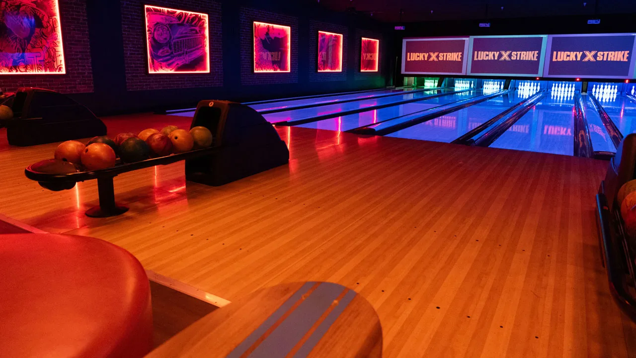 Beautiful bowling lanes with black lights and large TV screens above the lanes.